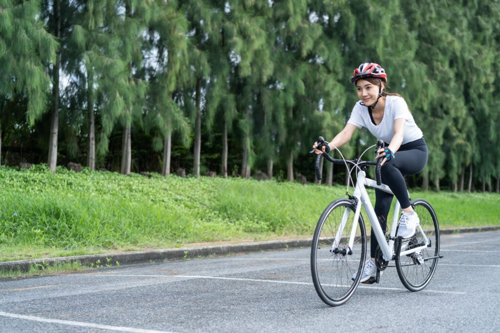 Asian young sport woman riding bicycle in the evening in public park.